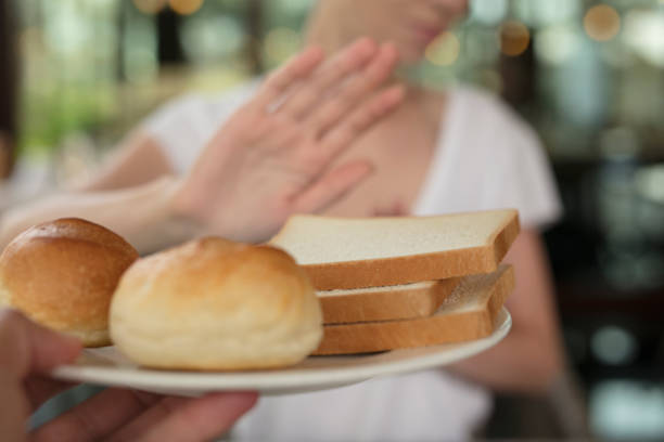 istock Gluten intolerance and diet concept. Woman refuses to eat white bread. Selective focus on bread 824024054