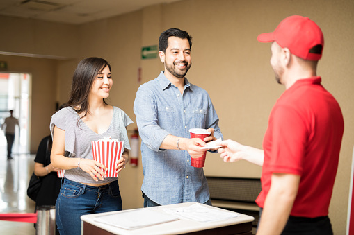 Portrait of a Hispanic couple handing over their tickets before watching a movie at the theater