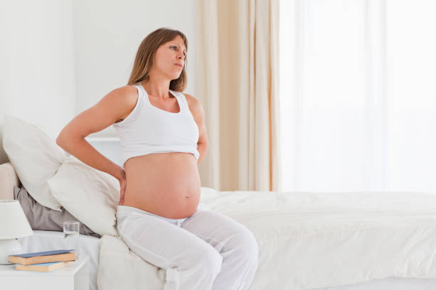 istock Attractive pregnant female having a back pain while sitting on a bed 824030124