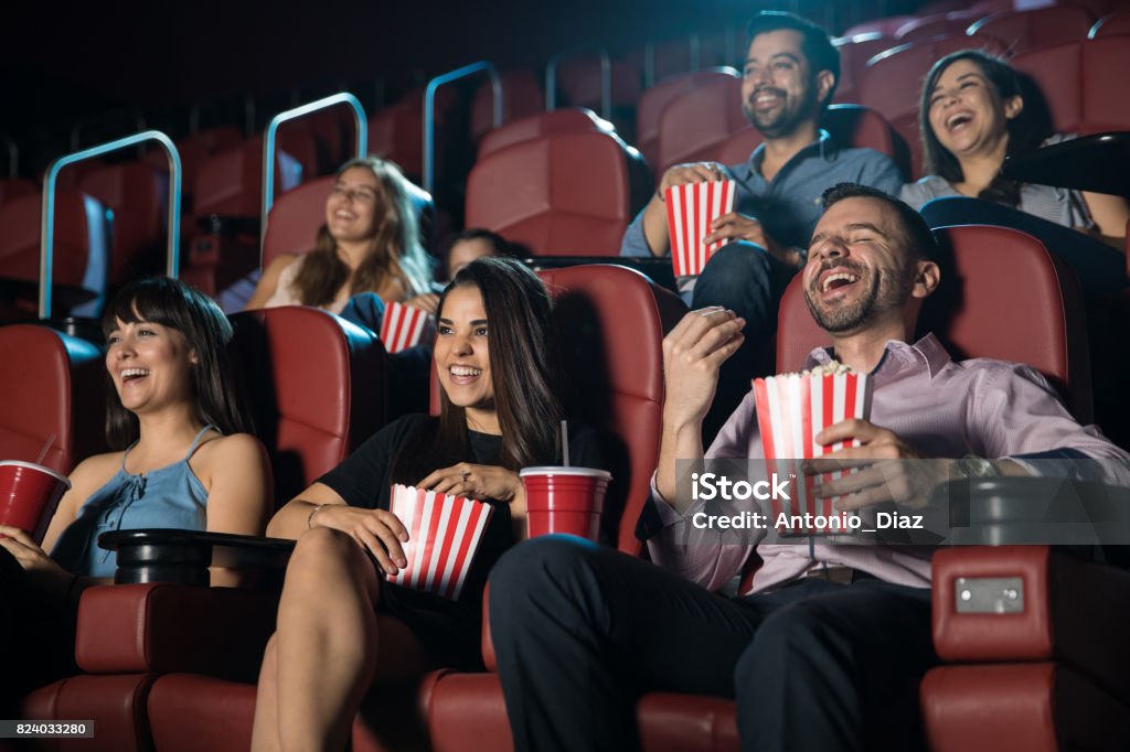 Group of people laughing at the movie theater Small audience of people laughing at the movie theater while watching a comedy and having a good time Movie Theater Stock Photo