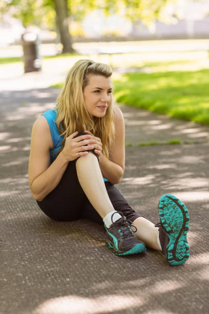 istock Fit blonde touching her injured knee on path 824033562