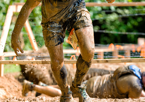 man rising out of barbwire mud pit in obstacle course
