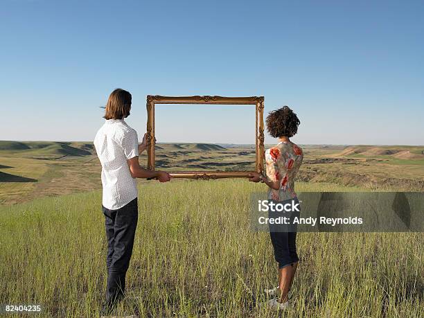 Foto de Homem E Mulher Segurando A Terra Quadro Em Aberto e mais fotos de stock de Moldura de Quadro - Equipamento de arte e artesanato - Moldura de Quadro - Equipamento de arte e artesanato, Segurar, Sonhador