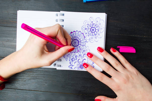 istock Female drawing flower shapes in notebook 824052672