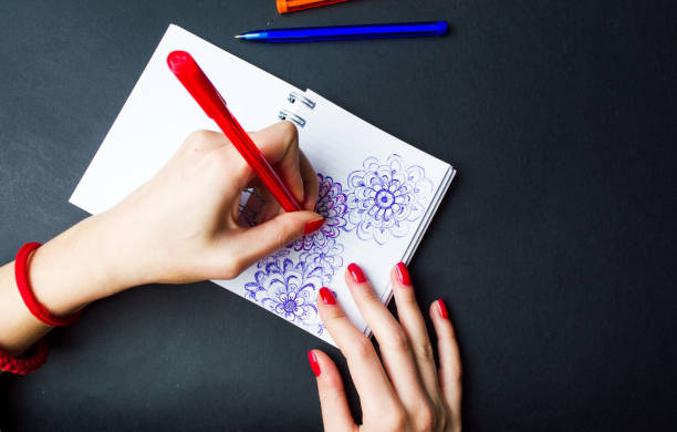 Female drawing flower shapes in notebook Female drawing flower shapes in a notebook left handed stock pictures, royalty-free photos & images