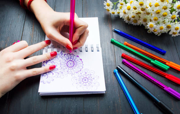 istock Female drawing flower shapes in notebook 824052962