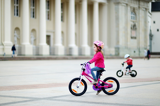 Adorable little girl riding a bike in a city
