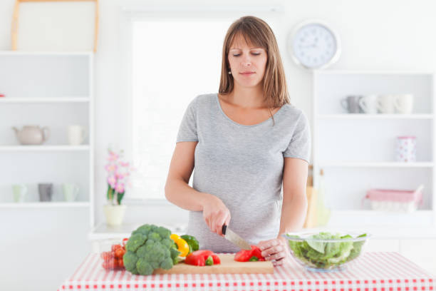 istock Attractive pregnant woman posing while cooking vegetables 824060908