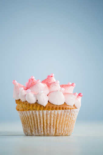 Close-up of pink cupcake on table against gray background