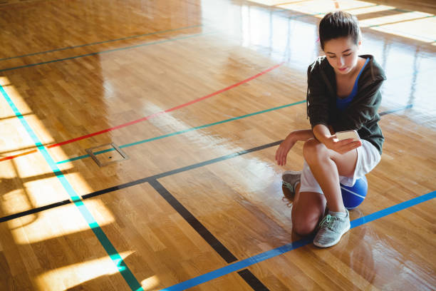 istock Female basketball player using mobile phone in court 824071336