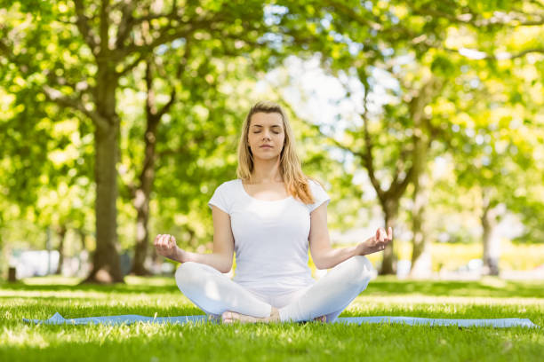istock Fit blonde sitting in lotus pose in the park 824072078