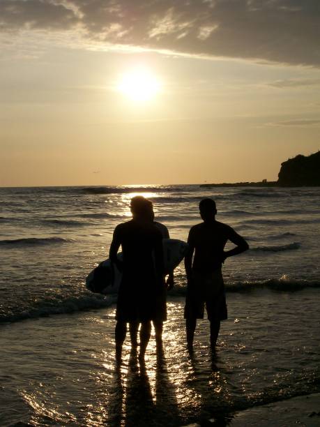 A group of athletic muscles sporties surfers friends taking a break after riding waves at sunset in Montañita beach in Ecuador, South America