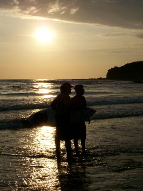 A group of athletic muscles sporties surfers friends taking a break after riding waves at sunset in Montañita beach in Ecuador, South America