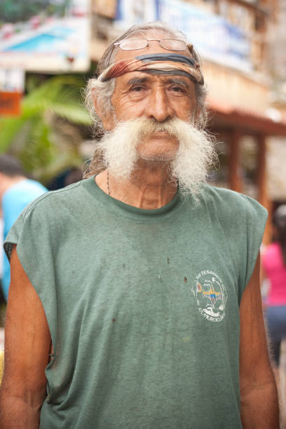 Montanita Portrait Montañita, Santa Elena, Ecuador - February 5, 2012: Portrait of a tourist older man walking at at the principal street on Montañita, Ecuador. Background some tiki stores. montanita ecuador stock pictures, royalty-free photos & images