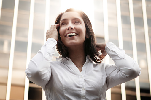 A happy businesswoman seen from below with building in background