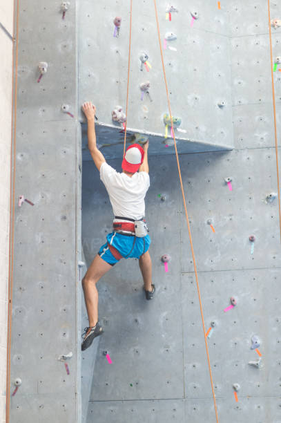 젊은 남자가 올라 실내 암벽 - climbing wall rock climbing holding reaching 뉴스 사진 이미지