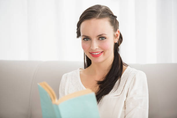 istock Pretty brunette reading book on couch 824122418