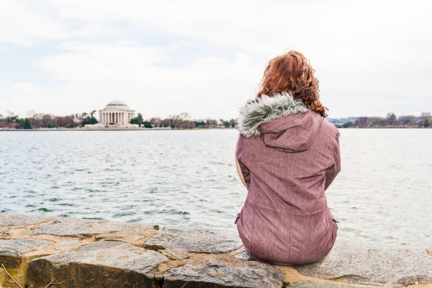 jeune femme assise sur bord dominant tidal basin et thomas jefferson memorial dans le parc - thomas coats photos et images de collection