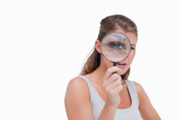 istock Young woman looking through a magnifying glass 824126794
