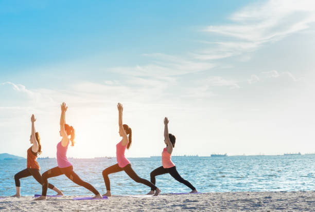 istock Young group yoga exercise with making warrior pose on the beach in summer 824139496