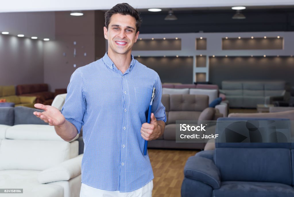 Smiling man seller showing prices in shop Smiling man seller showing prices in home furnishings store Salesman Stock Photo