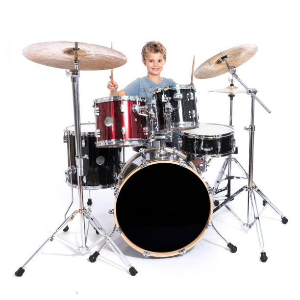 istock young caucasian boy plays drums in studio against white background 824164238