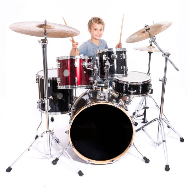 istock young caucasian boy plays drums in studio against white background 824164316