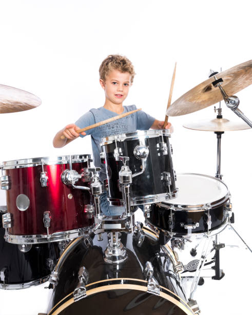 istock young caucasian boy plays drums in studio against white background 824164326