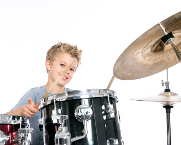 istock young caucasian boy plays drums in studio against white background 824164342