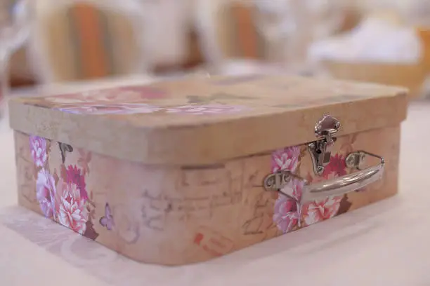 Horizontal shot of intricate rounded corner box, a typical money, gifts and memories gatherer at a wedding ceremony. Vintage box in pastel colors with floral print.