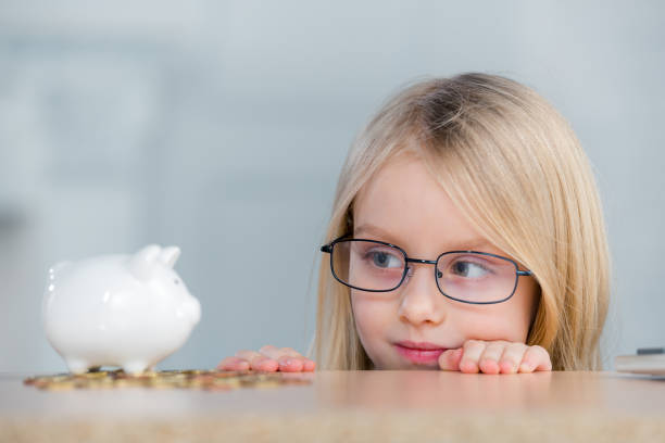 Teen girl with piggy bank on orange color background, portrait