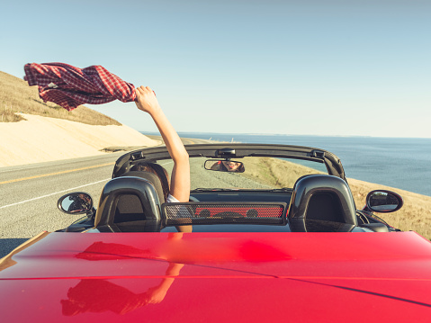 Woman driving car with arm in the air feeling the breeze at san juan island,usa.