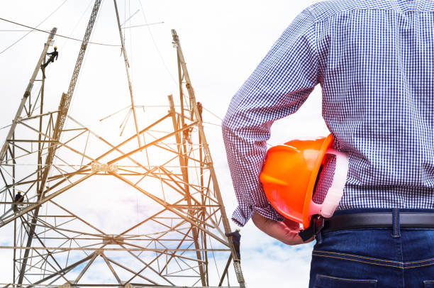 istock engineer holding safety helmet with electricians working on pylon . 824185518