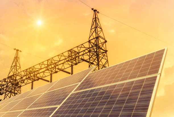 istock solar cells with high voltage electric pylon substation on sunset. 824186388