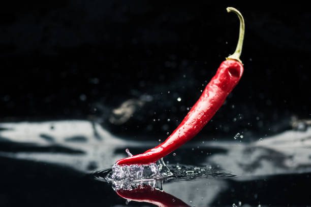 chili pepper caindo na água - red chili pepper - fotografias e filmes do acervo