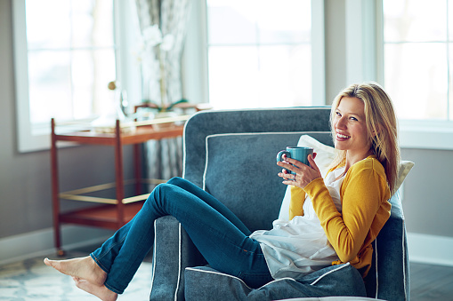 Shot of a young woman relaxing on her sofa with a cup of coffee