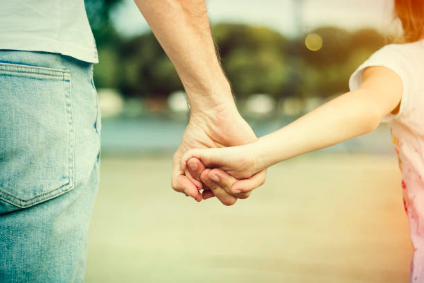 istock Father and daughter holding hands closeup 824193092