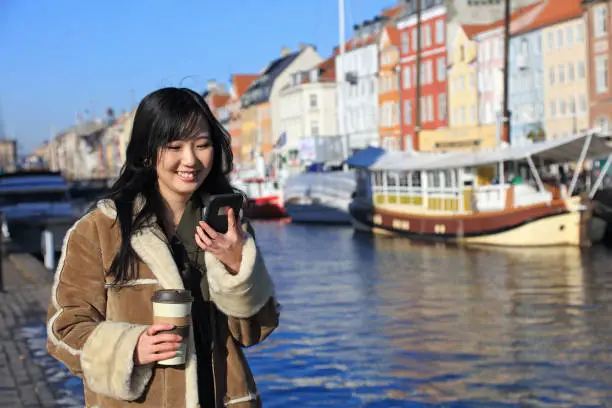 Vector illustration of Happy japanese woman using smartphone, Nyhavn, Copenhagen