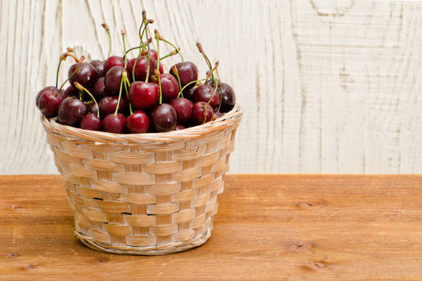 istock Basket with cherries on a wooden table, empty space 824223904