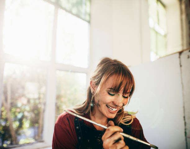 istock Female artist smiling with paint brush in studio 824231180