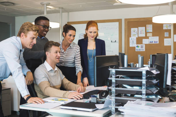 istock Colleagues standing by businessman working on computer in office 824241564