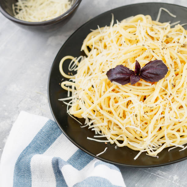 istock Black plate with Italian spaghetti with basil and parmesan on a gray table 824242518