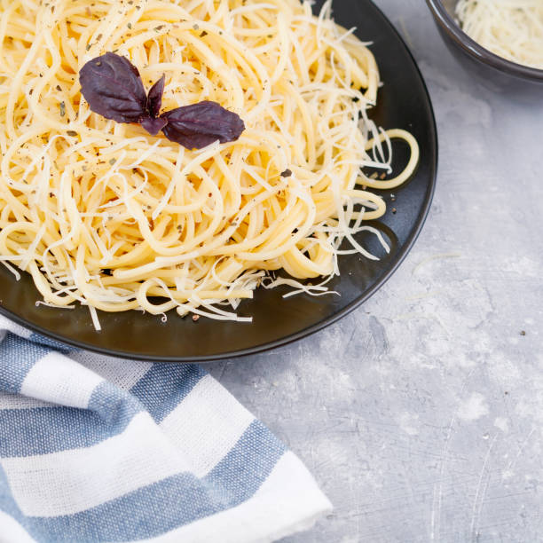 istock Black plate with Italian spaghetti with basil and parmesan on a gray table 824242596