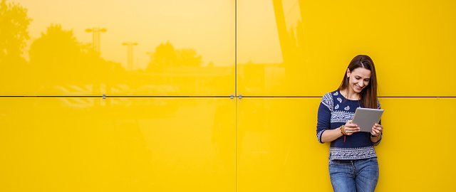 One woman, standing outdoors, using digital tablet.