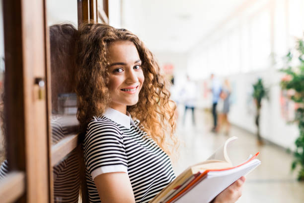 istock Teenage girl with notebooks in high school hall during break. 824254936