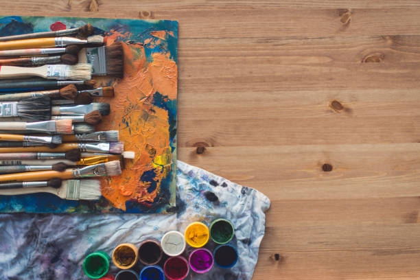 istock Different size paintbrush collection on an old palette with oil paint colors blend and a gouache set, top view picture. 824255044