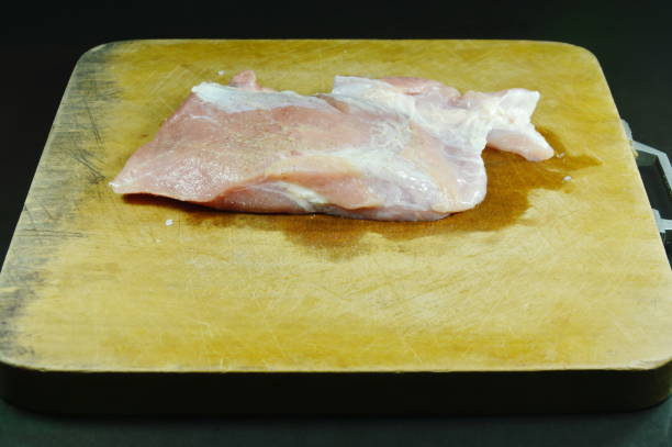 raw pork tenderloin marinated with salt and pepper on wooden chop block