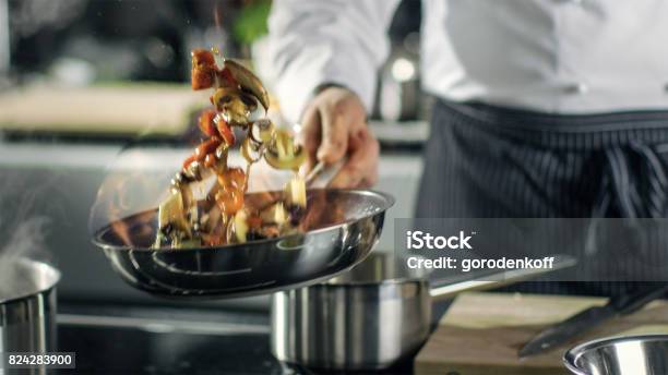 Professional Chef Cooks Flambe Style He Prepares Dish In A Pan With Open Flames He Works In A Modern Kitchen With Different Ingredients Lying Around Stock Photo - Download Image Now