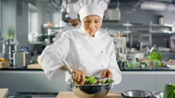 Photo of In a Famous Restaurant Female Cook Prepares Salad. She Works in a Big Modern Kitchen.