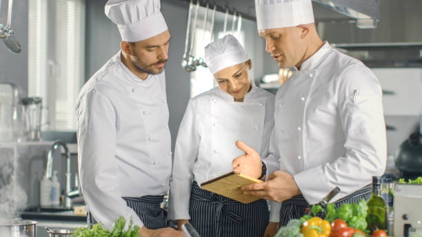 istock In the Modern Kitchen Team of Cooks Use Tablet Computer For Recipes, They Smile and Have Discussion. Kitchen is Full of Food Ingredients, Vegetables, Meat, Boiling Soup. 824284032
